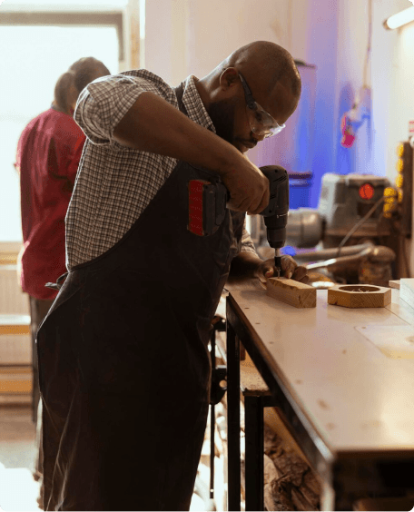 Hill Rising craftsman drilling timber at a workbench in the Polokwane workshop